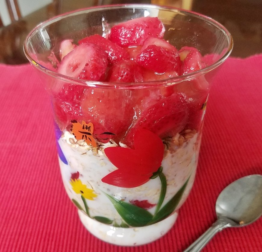 Oats and sliced strawberries layered in a glass